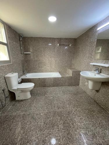 uma casa de banho com uma banheira, um WC e um lavatório. em Flamingo Cottages em Manama