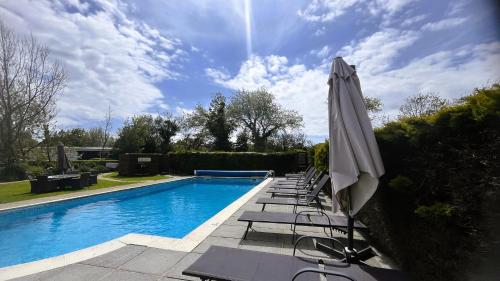 uma piscina com cadeiras e um guarda-sol em Le Friquet Hotel em Castel