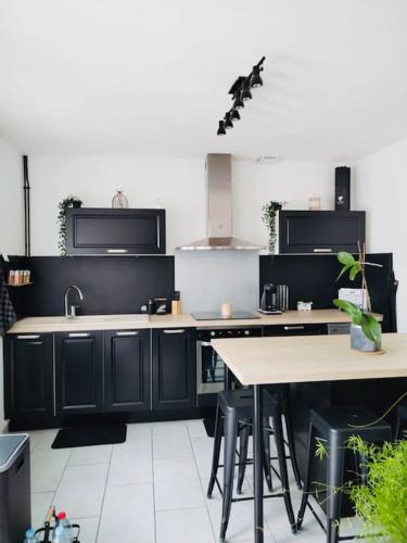 une cuisine avec des armoires noires, un évier et des tables dans l'établissement Maison 6 pers Elle est Moi, à Romorantin-Lanthenay