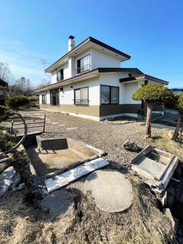 a white house with a tree in front of it at アラン別邸自然溢れる呼人の一軒家 in Yobito