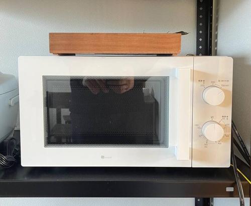 a microwave oven on a shelf with a person in it at アラン別邸自然溢れる呼人の一軒家 in Yobito