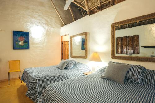 a bedroom with two beds and a mirror on the wall at Junto al Rio Bungalows & Suites in Sayulita