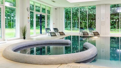 a room with a pool with chairs and windows at Muthu Clumber Park Hotel and Spa in Worksop