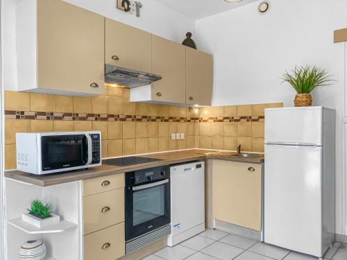 Il comprend une cuisine équipée d'appareils électroménagers blancs et d'un réfrigérateur blanc. dans l'établissement Evasion Côtière Oléron, à Bourcefranc