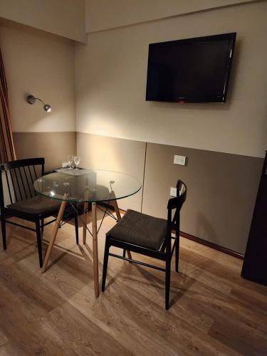 a dining room with a glass table and chairs and a television at Hotel Riogrande in Santa Fe