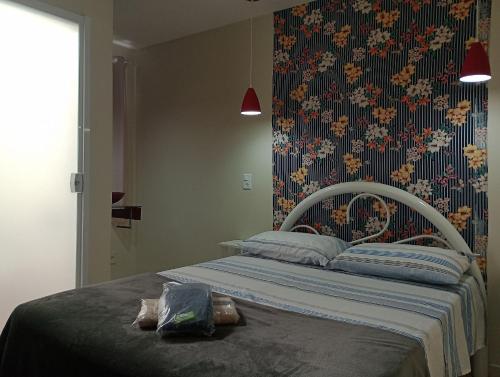 een slaapkamer met een bed met bloemenbehang bij HoStel de Setiba - HOSPEDARIA OCA RUCA in Guarapari