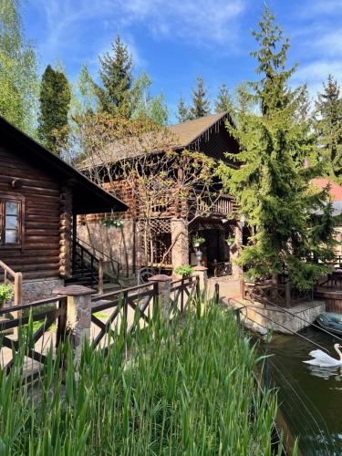 una casa de madera con un estanque delante de ella en Vik-Jan en Khmelʼnytsʼkyy