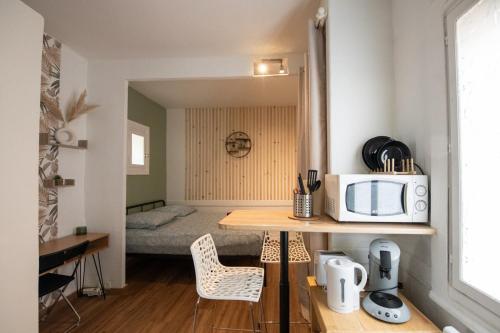une petite cuisine avec une table avec un micro-ondes et un lit dans l'établissement Zola - Joli studio tout confort Villeurbanne, à Villeurbanne