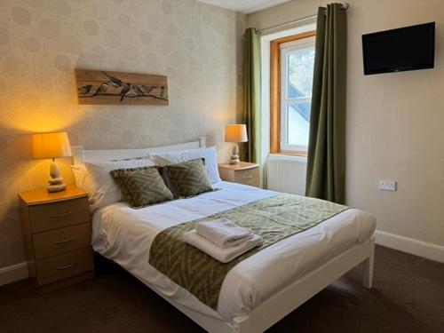 ein Schlafzimmer mit einem Bett mit zwei Lampen und einem Fenster in der Unterkunft Lochranza Country Inn in Lochranza
