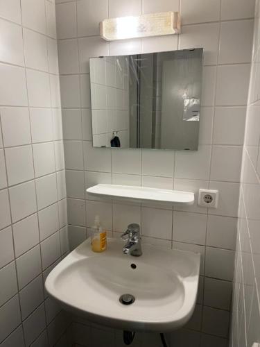 W białej łazience znajduje się umywalka i lustro. w obiekcie Bungalow direkt am See - Toilette und Dusche in separatem Gebäude w Berlinie