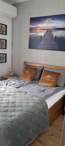 a bedroom with a bed with a painting of a pier at Apartament Drwęcka in Ostróda