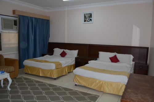ein Hotelzimmer mit 2 Betten und roten Kissen in der Unterkunft الراقية للوحدات السكنية المفروشة in Medina