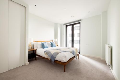 Schlafzimmer mit einem Bett mit blauen Kissen und einem Schreibtisch in der Unterkunft London Croydon by Charles Hope in Croydon