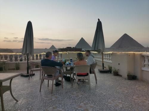 a group of people sitting at a table with the pyramids in the background at Explore Stars Pyramids View in Cairo