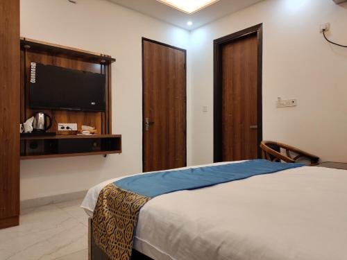 a bedroom with a bed and a flat screen tv at MK Regency in Greater Noida