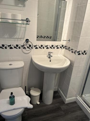 a white bathroom with a sink and a toilet at Harbour Lights Guest House Room Only in Weymouth