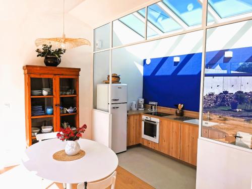 une cuisine avec un réfrigérateur blanc et une table dans l'établissement L Atelier de Dimitri a 500m de la Plage, à Barbâtre