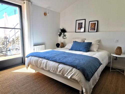 une chambre avec un grand lit et une grande fenêtre dans l'établissement L Atelier de Dimitri a 500m de la Plage, à Barbâtre