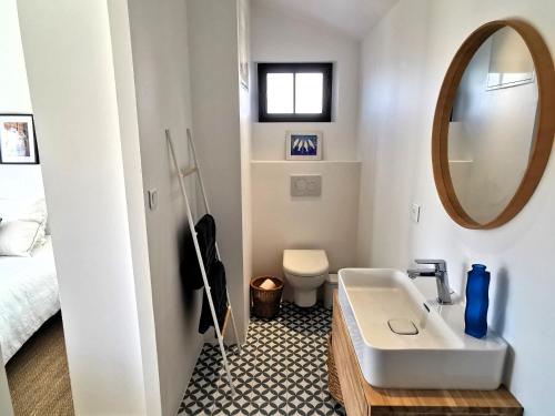 une salle de bain blanche avec un lavabo et un miroir dans l'établissement L Atelier de Dimitri a 500m de la Plage, à Barbâtre