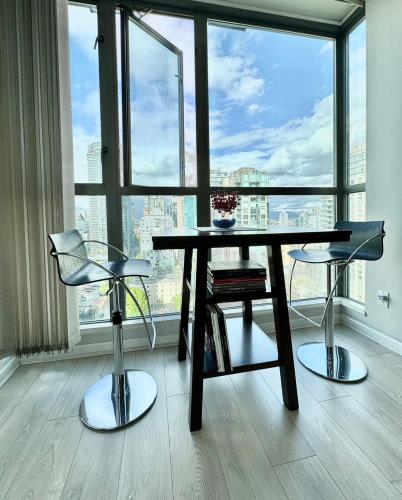 a table and two chairs in front of a large window at Richard Comfort Living in Vancouver
