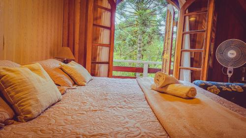 a large bed in a room with a large window at Pousada Atalaia Capivari in Campos do Jordão