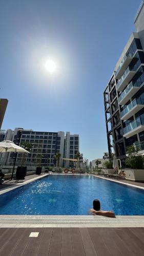 a man laying in a swimming pool next to some buildings at Luxury Studio Brand New with HighEnd Furnishings in Dubai