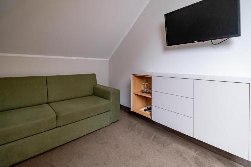 a living room with a green couch and a flat screen tv at Relax Hotel Stork in Lednice
