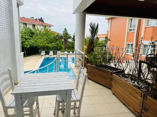 a table and chairs on a balcony with a pool at WHITE MANSION in Arnavutköy