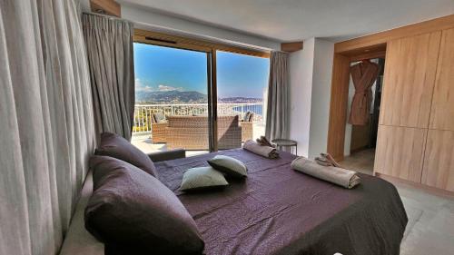 une chambre avec un grand lit avec une grande fenêtre dans l'établissement Appartement 2 chambres et studio indépendant avec vue sur mer, à Nice