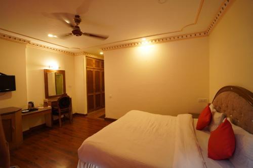 een slaapkamer met een bed, een bureau en een televisie bij roy castle in Dharamshala