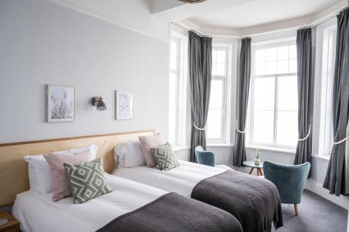 2 camas en una habitación de hotel con ventanas en The Kingswood Hotel, en Sidmouth