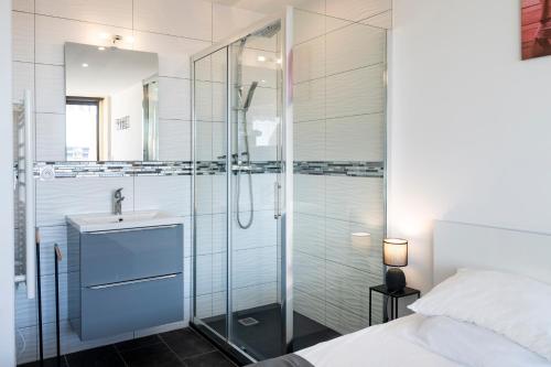 La salle de bains est pourvue d'une douche et d'un lavabo à côté d'un lit. dans l'établissement Studio Village Naturiste Héliopolis Exultation, au Cap d'Agde