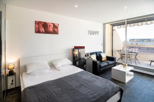 une chambre avec un lit, un canapé et une fenêtre dans l'établissement Studio Village Naturiste Héliopolis Exultation, au Cap d'Agde