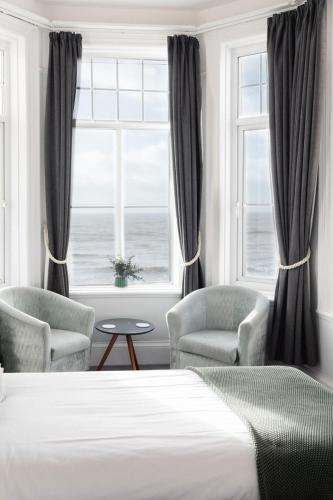 a bedroom with a bed and two chairs and a window at The Kingswood Hotel in Sidmouth