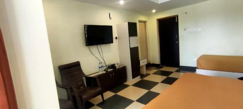 a room with a bed and a television on a wall at Srirathna Temple View Inn in Thanjāvūr