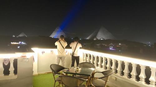 dos hombres parados en un balcón por la noche en Explore Stars Pyramids View, en El Cairo