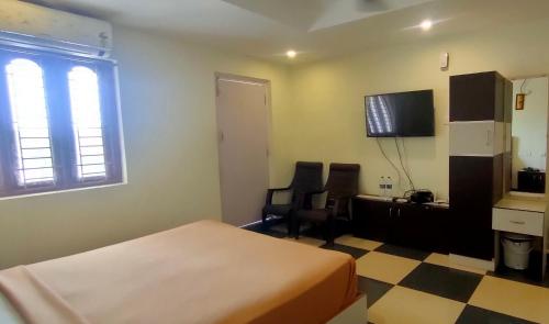 a hotel room with a bed and two chairs and a television at Srirathna Temple View Inn in Thanjāvūr