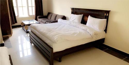 um quarto com uma cama grande e um sofá em Magnum Hotel em Battakundi