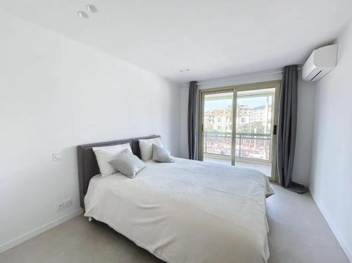 une chambre avec un lit blanc avec une grande fenêtre dans l'établissement Modern 2 Bedroom in the Heart of Cannes, à Cannes