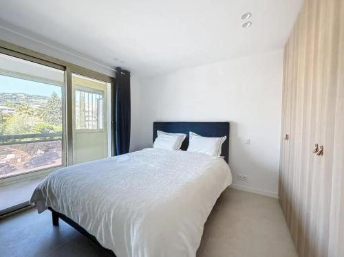 une chambre avec un grand lit avec une grande fenêtre dans l'établissement Modern 2 Bedroom in the Heart of Cannes, à Cannes