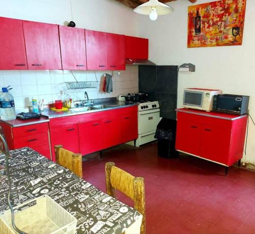 cocina con armarios rojos, fregadero y microondas en Casa Rural Los Coirones 6Pax By Inside en Tupungato