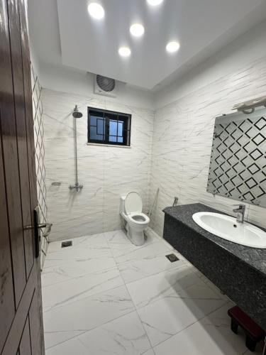 een witte badkamer met een toilet en een wastafel bij Dream Executive Guest House in Islamabad