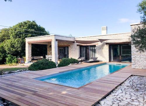 une piscine avec une terrasse en bois à côté d'une maison dans l'établissement Villa Bohème-chic, à Bonifacio