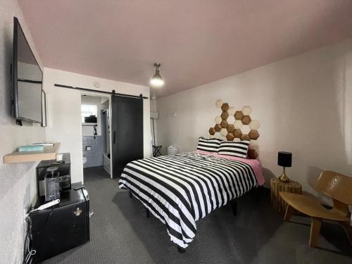 Rainbow Motel في غريلي: غرفة نوم بسرير وبطانية مخططة سوداء وبيضاء