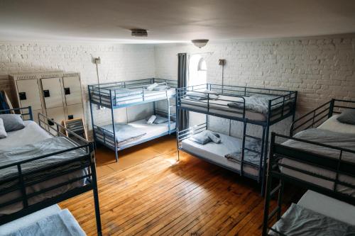 three bunk beds in a room with wooden floors at Saintlo Ottawa Jail Hostel in Ottawa