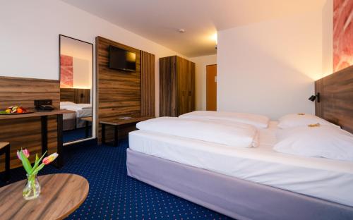 una camera d'albergo con due letti e una scrivania di City Hotel Fortuna Reutlingen a Reutlingen