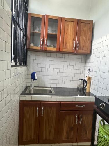 una cocina con armarios de madera y fregadero en Stay with me 5, en Dar es Salaam