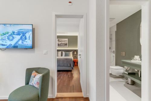 a room with a bedroom with a bed and a chair at Waldst&auml;tterhof Swiss Quality Hotel in Luzern