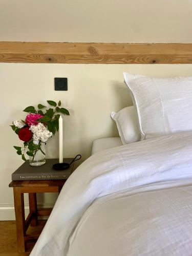 a bed with a table with a vase of flowers on it at Edda Country House - Val de Loire in Onzain