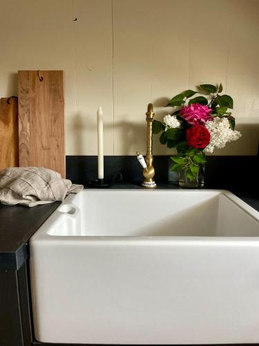 a white sink with a candle and a vase of flowers at Edda Country House - Val de Loire in Onzain